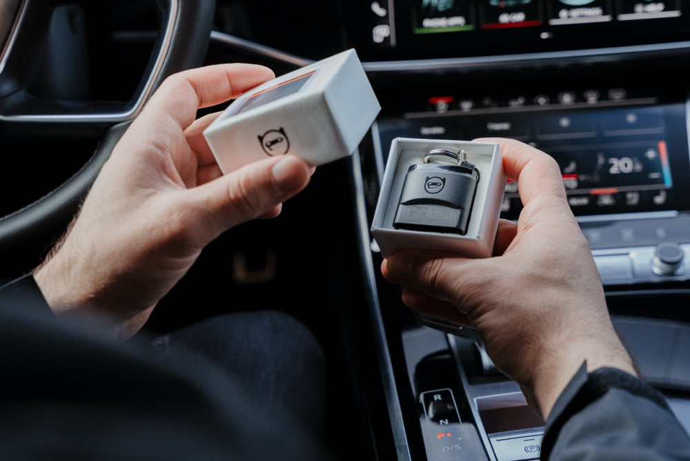 OBDeleven adapter in hand with an Audi with key